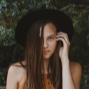 A young woman wearing a black sun-hat wiht half of her hair covering her face.