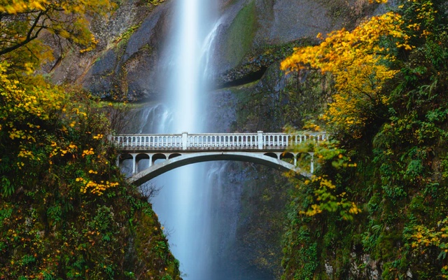 A picture of waterfall behind a bridge.