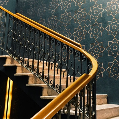 A picture of staircase with a wall of mosaic print.